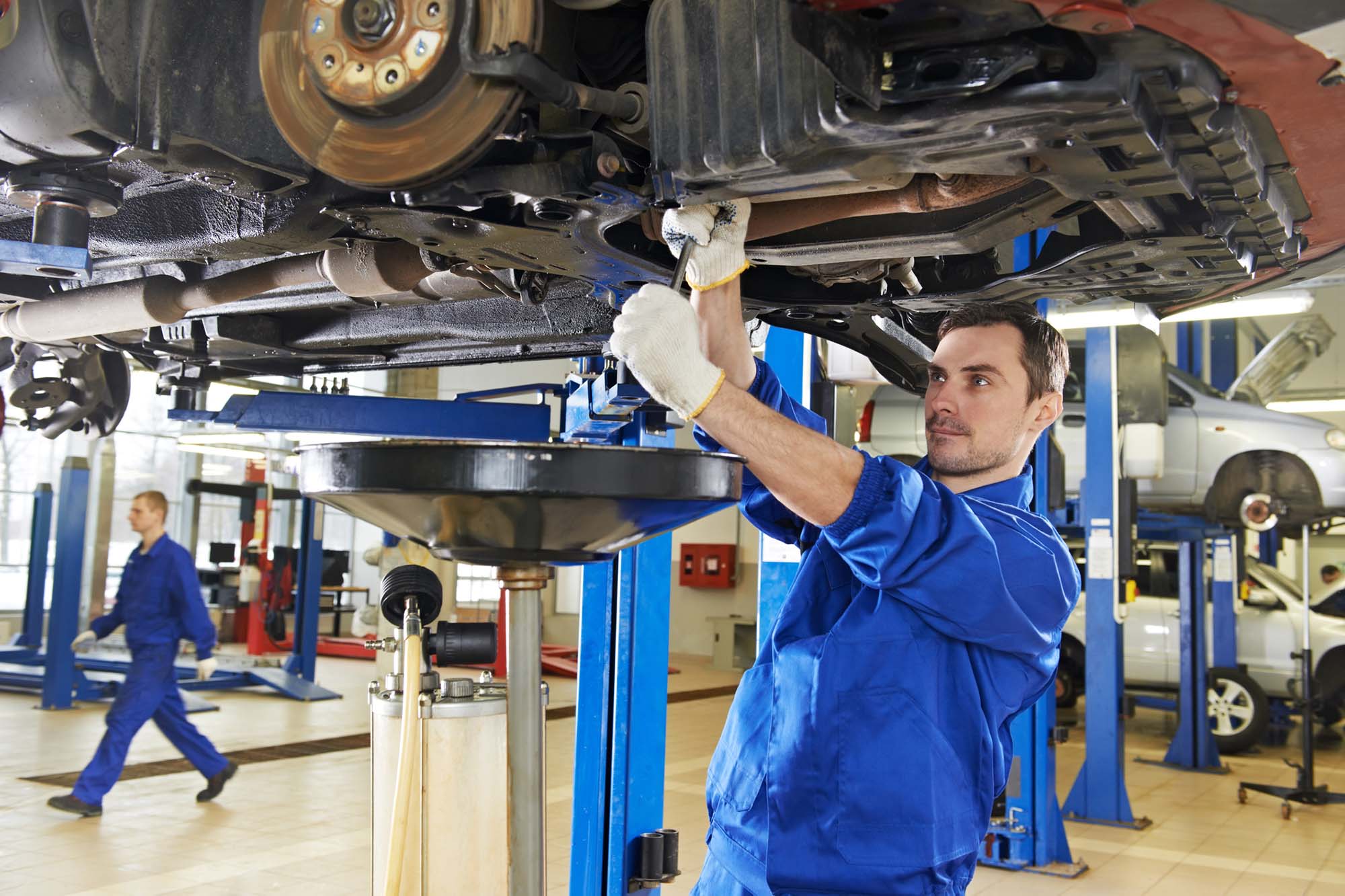 Car mechanics repairing a car on hydraulic lift